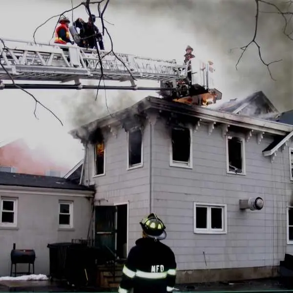 A firefighter is on the roof of a house.