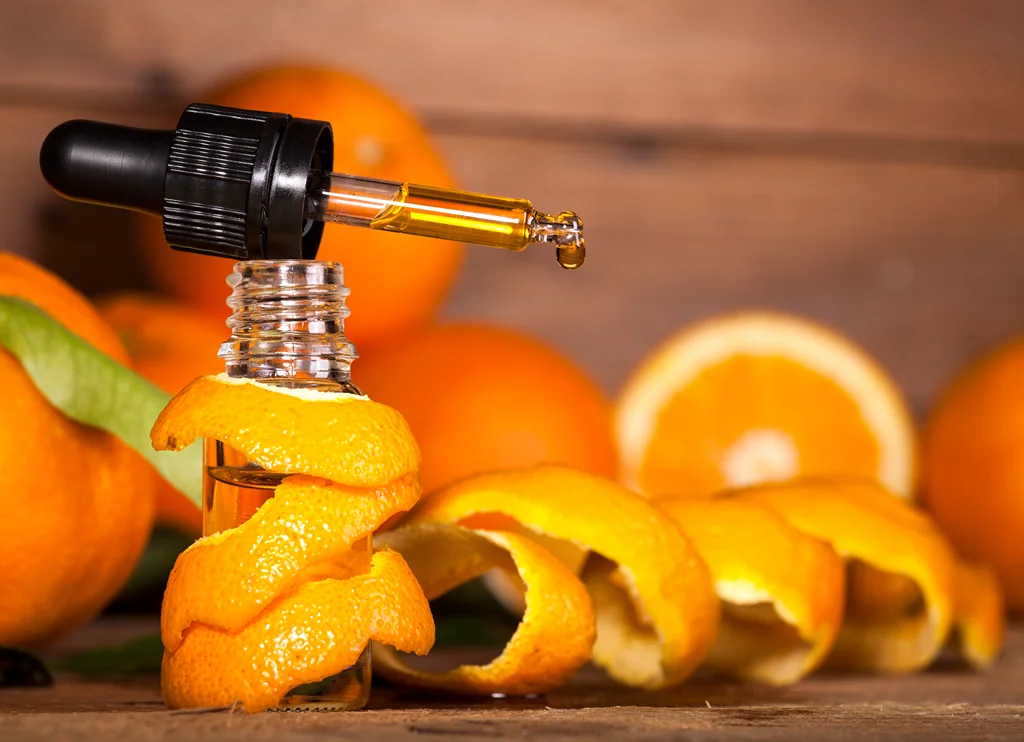 Orange fruits and a bottle with orange peel around and a dropper on top.